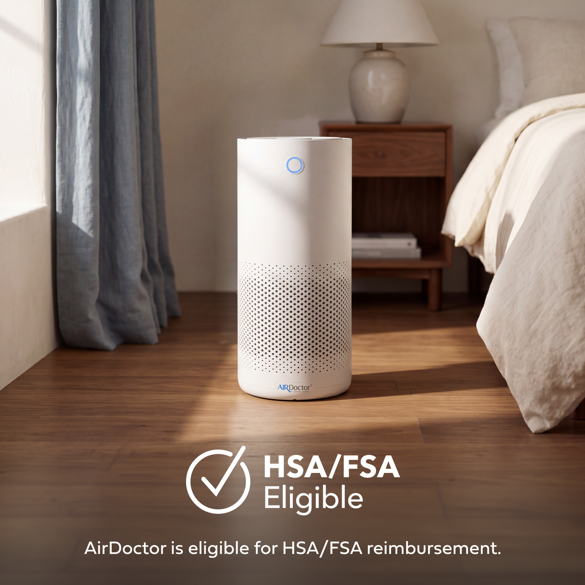 A white cylindrical AirDoctor air purifier stands on a wooden floor in a softly lit bedroom, with a nightstand, lamp, and bed visible in the background. Text at the bottom reads 'HSA/FSA Eligible' and 'AirDoctor is eligible for HSA/FSA reimbursement.