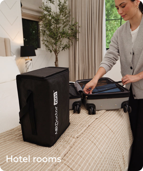 A hotel room with an Airdoctor GO! on the the bed