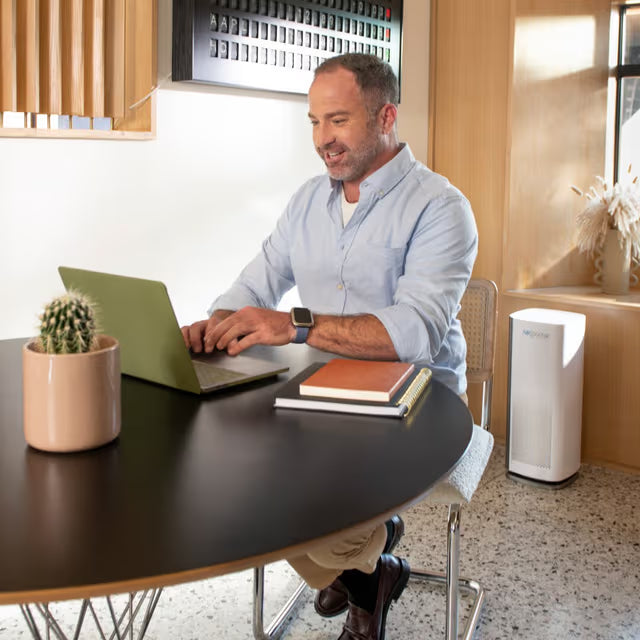 AirDoctor 1000 air purifier in an office space with man working at desk